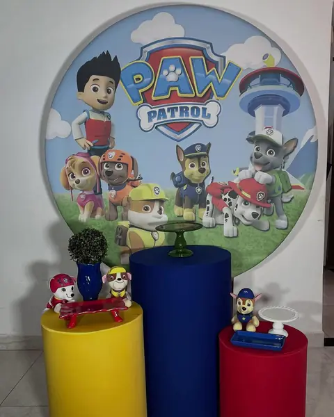 Kit de decoração tema Patrulha Canina montado: painel redondo com os personagens e três cilindros nas cores amarelo, azul e vermelho